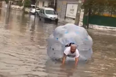Sağanakta suyla dolan caddede içine girdiği büyük şeffaf balonla ilerledi